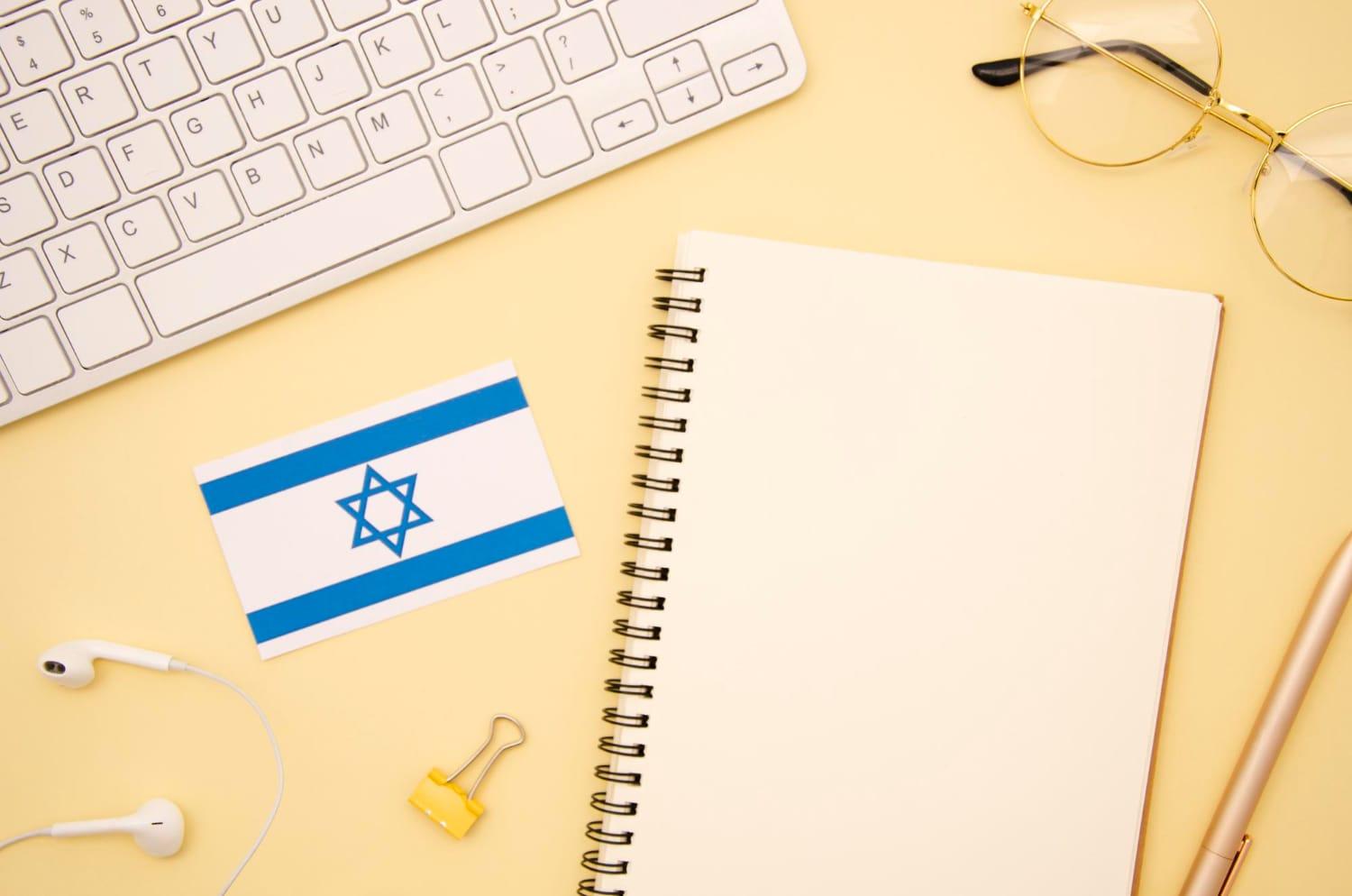 שולחן עבודה עם מחברת, מקלדת ודגל ישראל – הכנה למבחני נציבות שירות המדינה